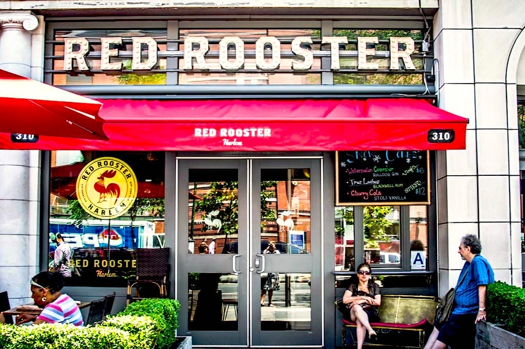 Red Rooster Harlem, restaurant culte et musical Façade du Red Rooster, restaurant emblématique de Harlem avec terrasse et store rouge