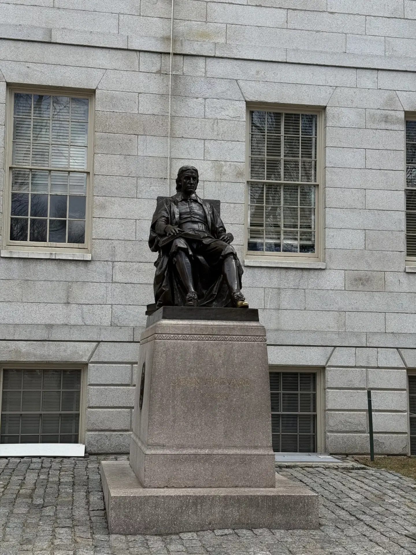 Estatua de John Harvard en el campus con turistas