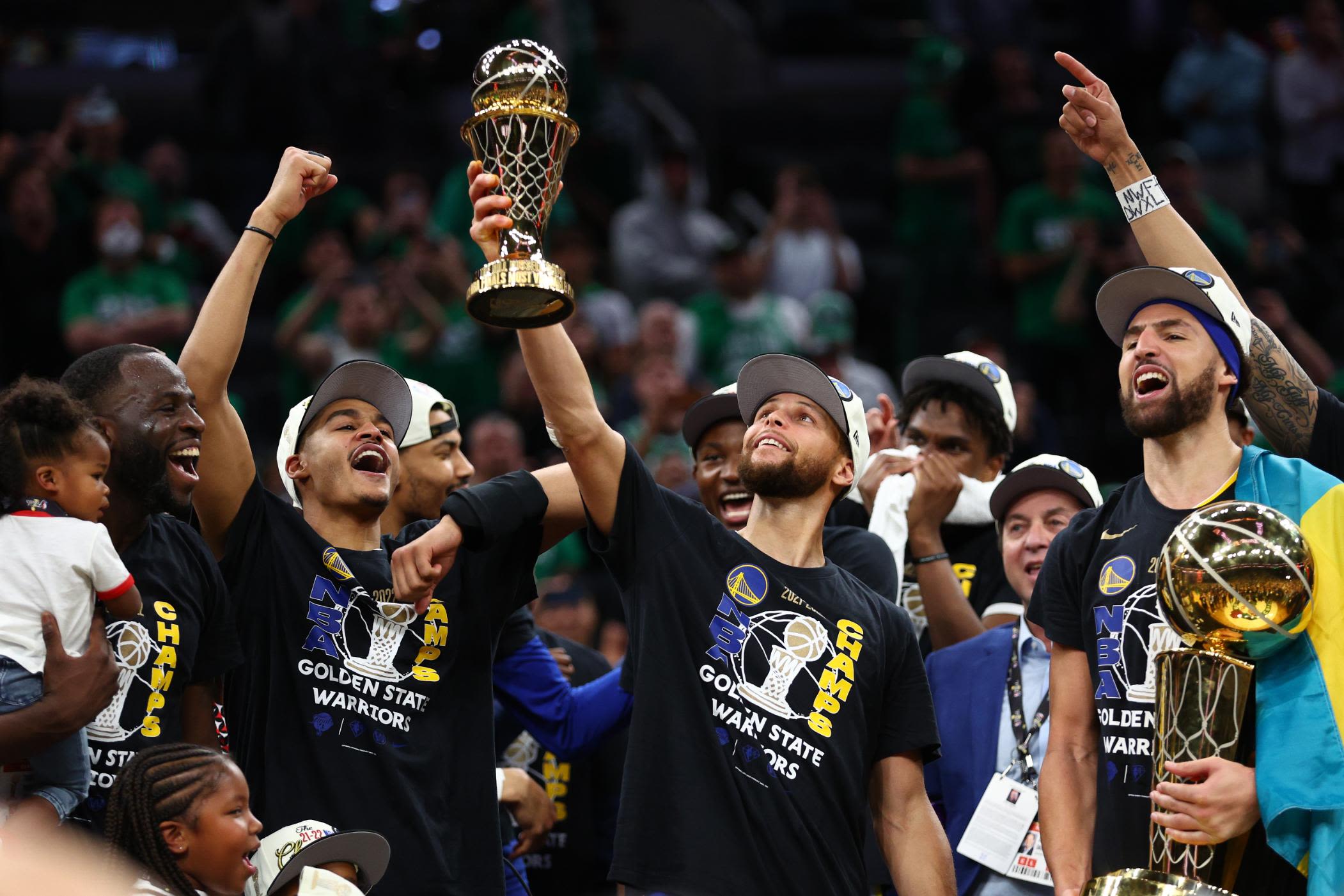 Stephen Curry brandit son trophée de MVP des Finales 2022 entouré de ses coéquipiers Warriors