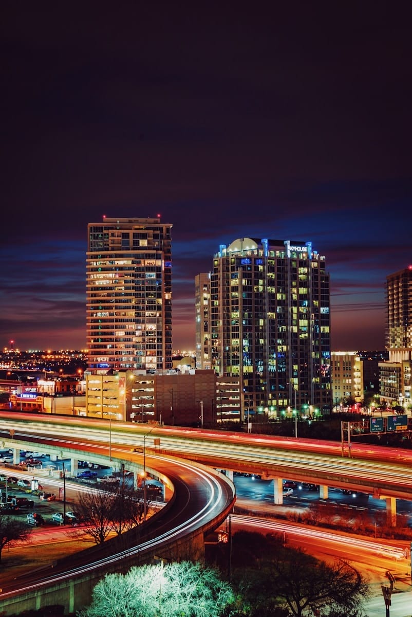 timelapse photography of red and orange light crossing on road near city during nighttime