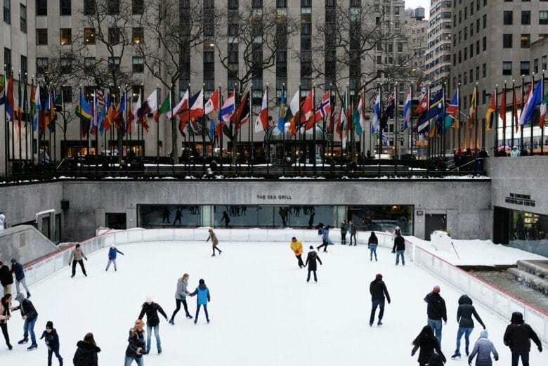 people ice skating on field surrounded by high-rise buildings