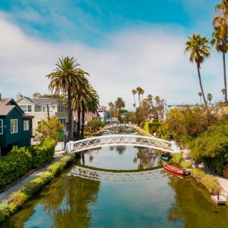 Vue des Venice Canals à Los Angeles avec pont blanc, maisons résidentielles et palmiers sous un ciel bleu