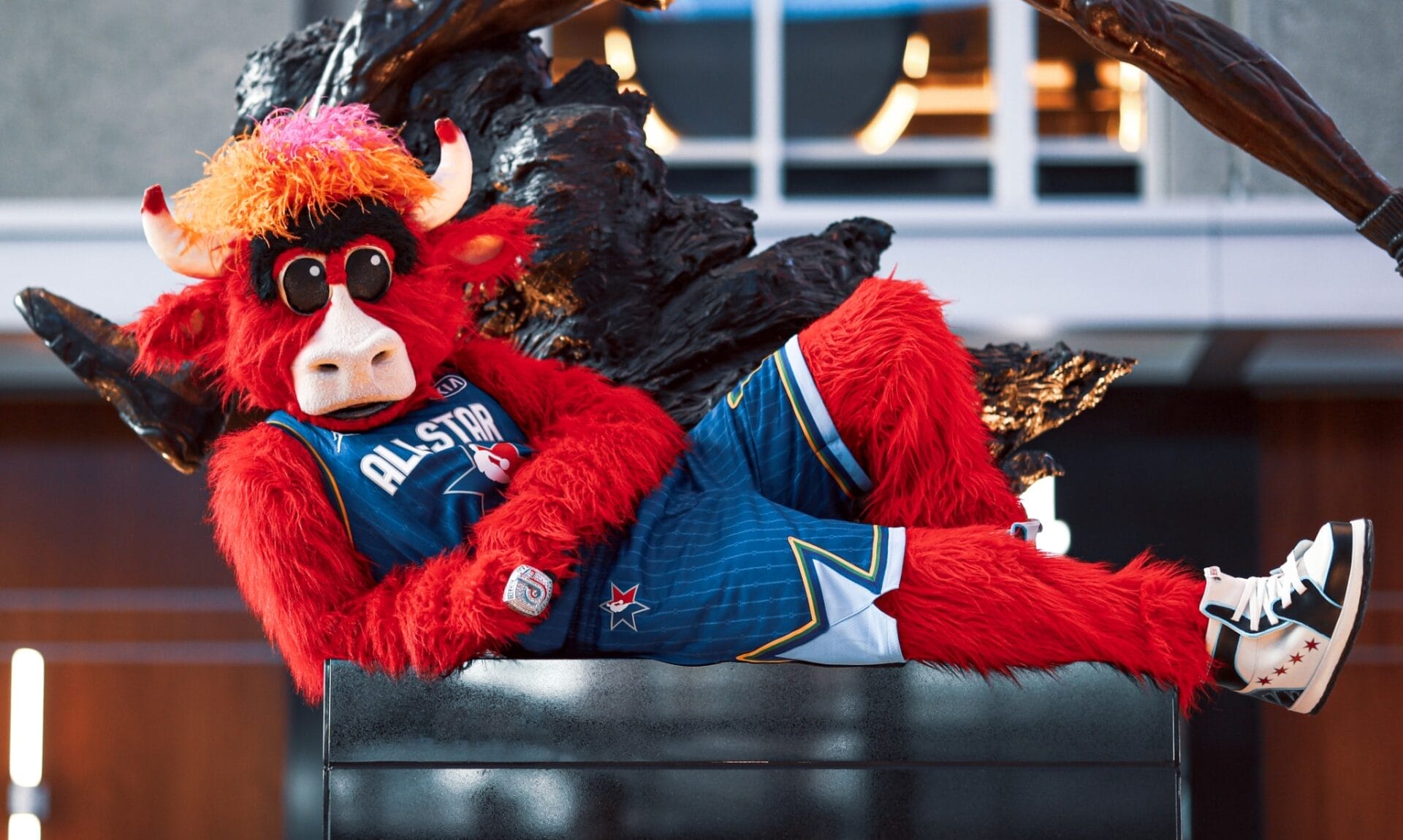 Benny the Bull, la mascotte iconique des Chicago Bulls, allongé en tenue All-Star devant la statue de Michael Jordan