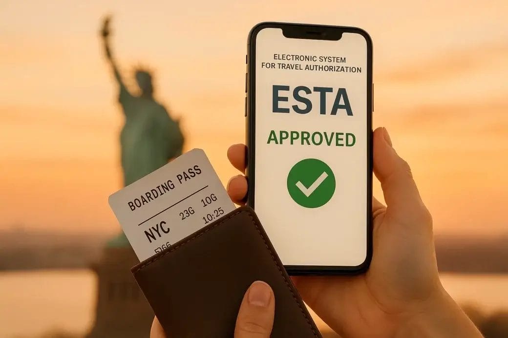 ESTA approuvée affichée sur smartphone, billet d’embarquement NYC en main, avec la Statue de la Liberté au crépuscule en arrière-plan