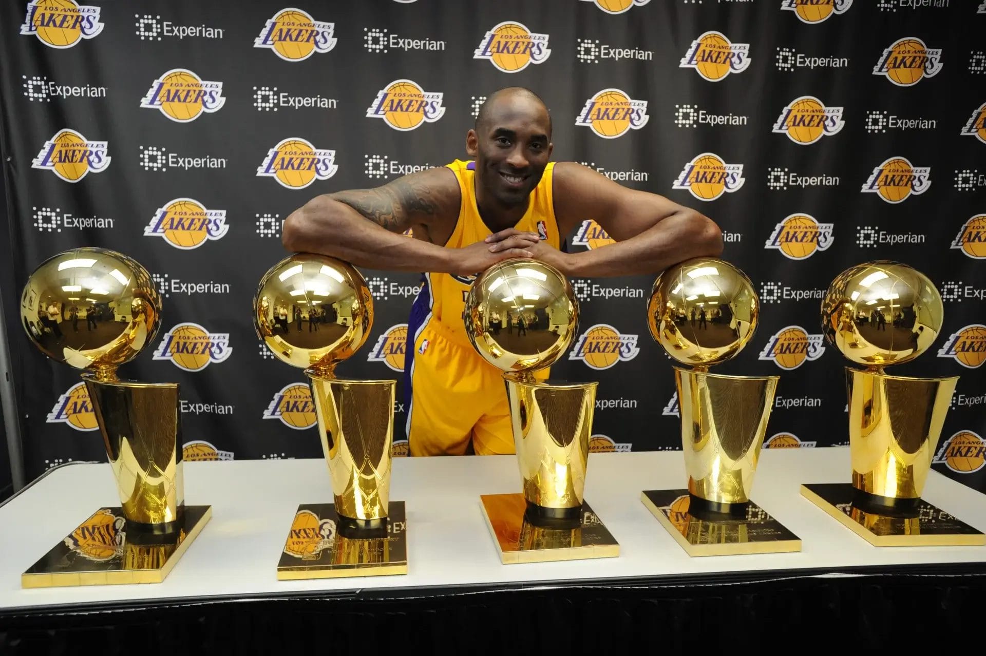 Kobe Bryant pose fièrement avec ses 5 trophées NBA sous le maillot des Lakers