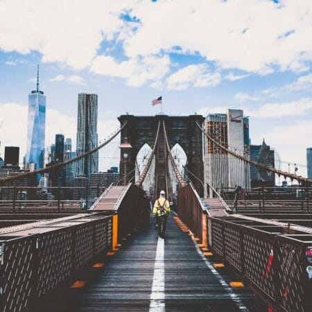 Iconic Brooklyn Bridge view with New York City skyline and construction worker.