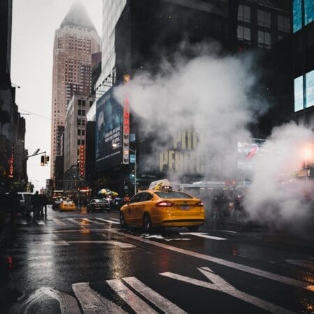 yellow taxi sedan on gray concrete street passed through white smokes near walking lane